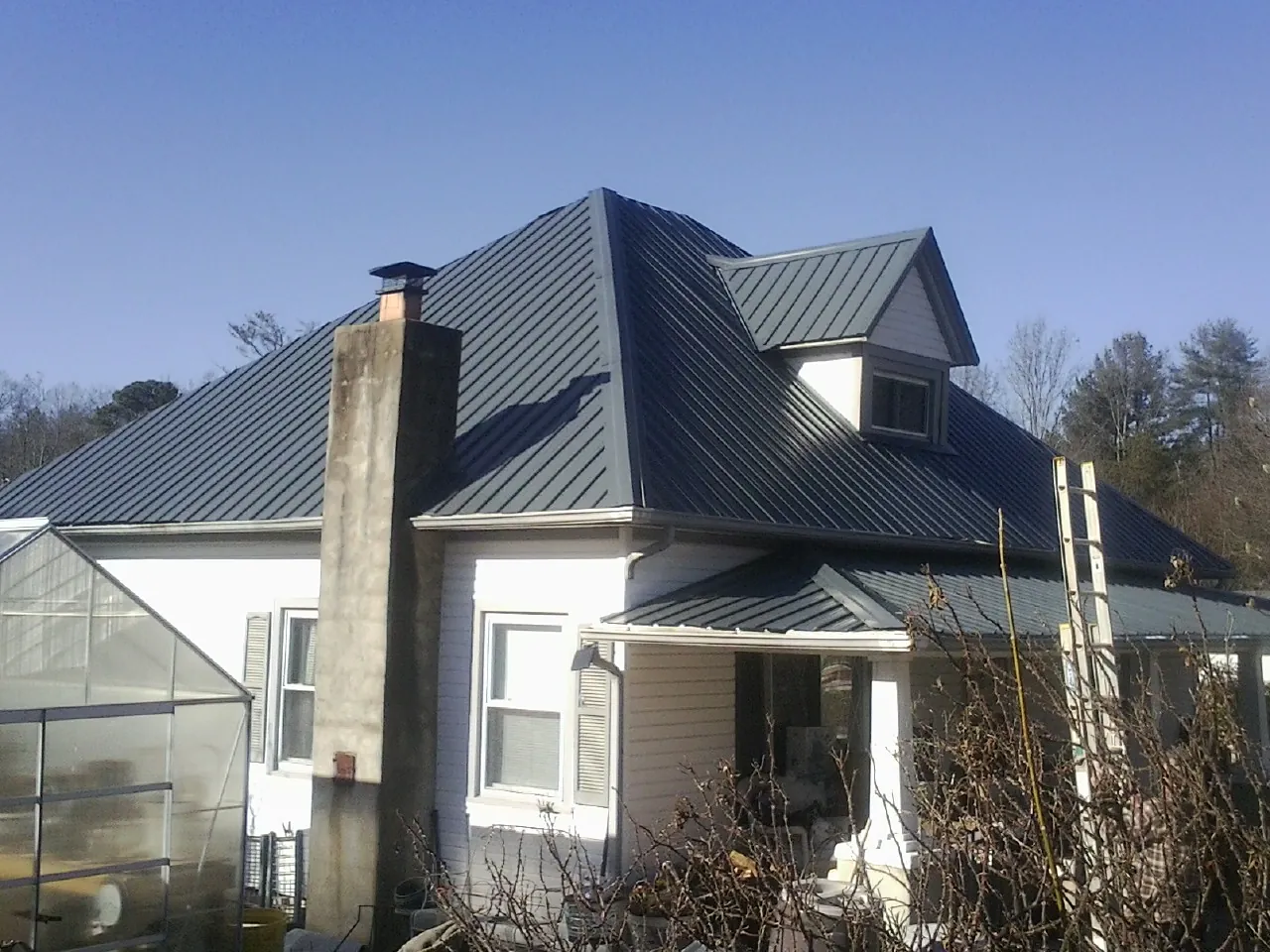 Dark blue standing seam metal roof on a white farmhouse with dormer in Fort Atkinson
