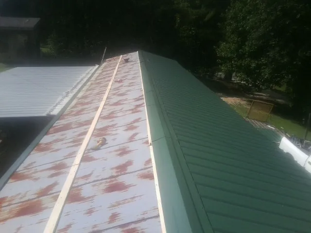 Old rusted panels beside newly installed green metal roofing — Wind Damage Roof Repair by Roofing Brothers in Fort Atkinson