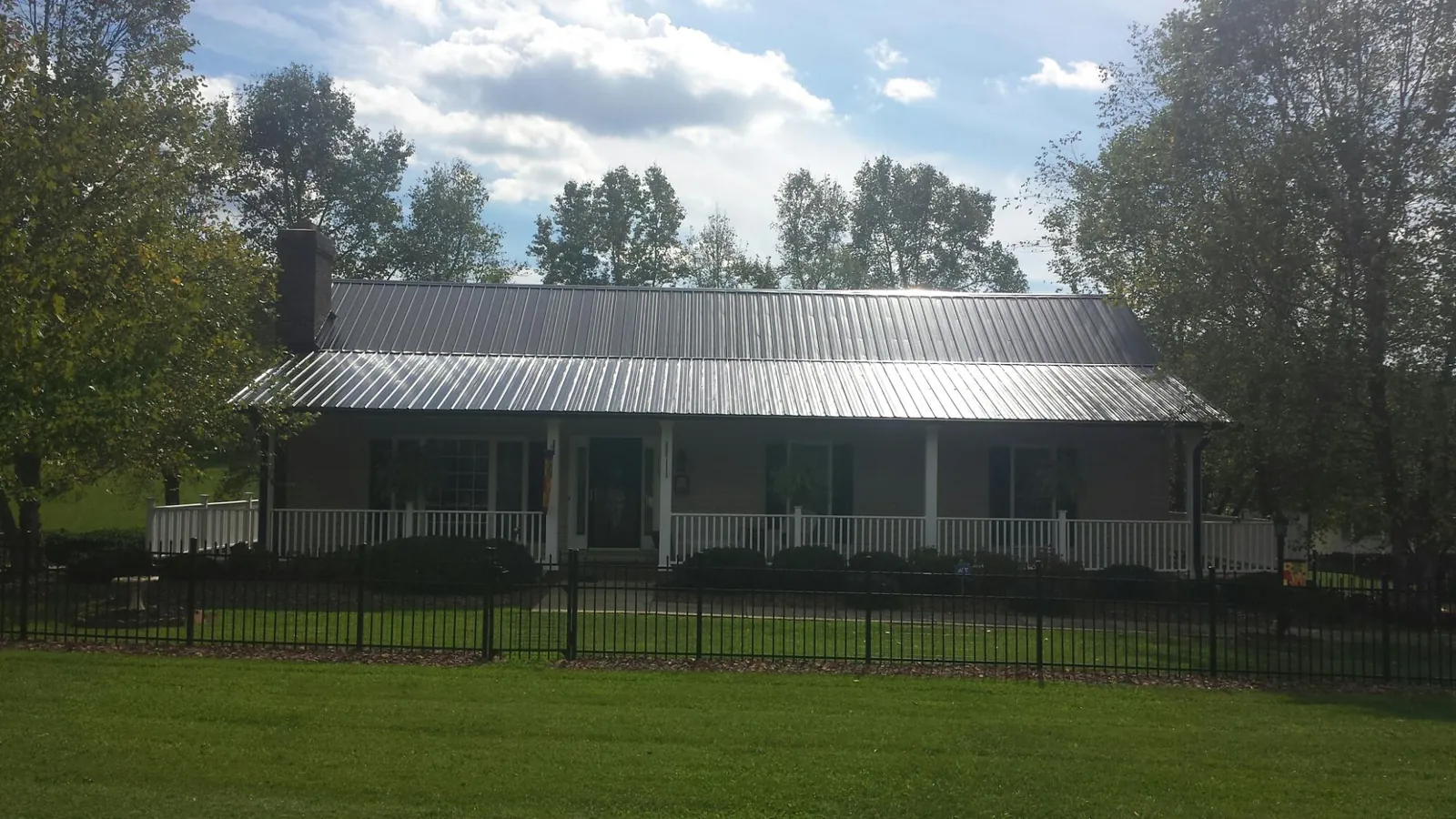 Gray metal roof on a brick ranch with a full width front porch — Gutter Guard Installation work by our crew in Fort Atkinson