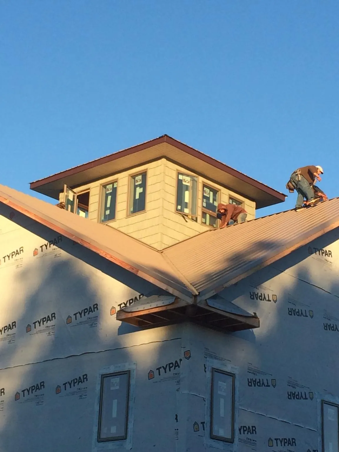 Roofers working around a rooftop cupola on a new metal roof at sunset — Roof Waterproofing in Fort Atkinson by Roofing Brothers